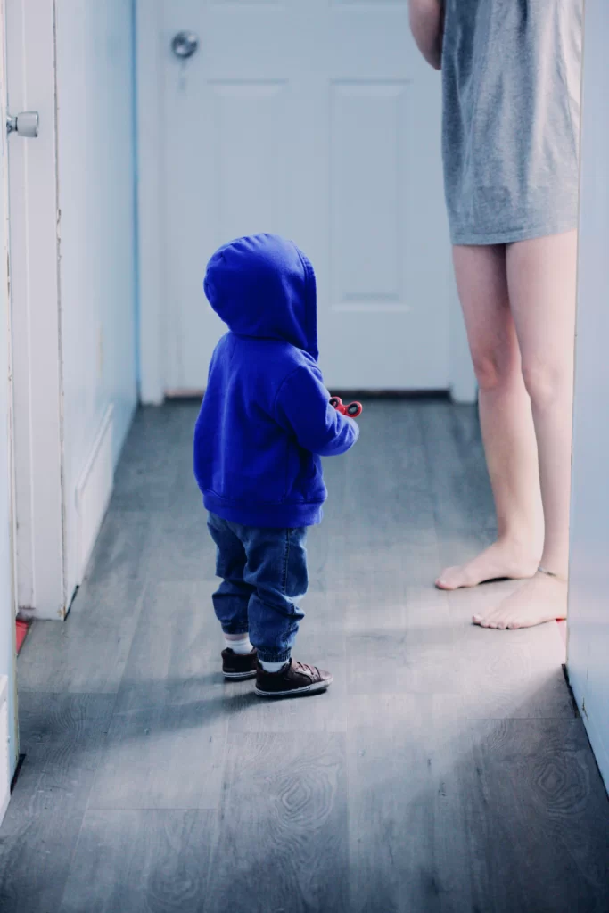 woman coming out of bathroom to toddler standing waiting
