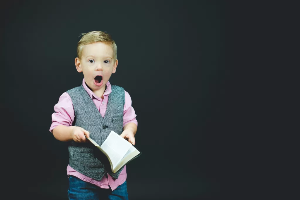 little boy holding book with shocked face